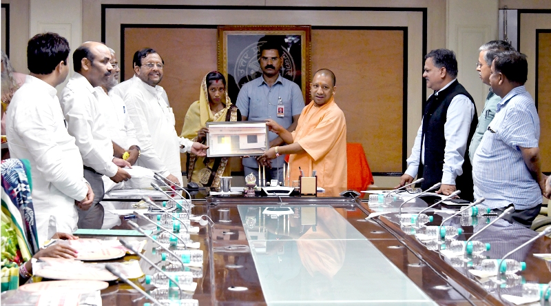 UPCM लाभार्थी को प्रतीकात्मक चिन्ह प्रदान करते हुए