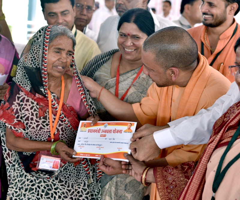 UPCM लाभार्थी को प्रधानमन्त्री उज्जवला योजना का प्रमाण पत्र प्रदान करते हुए
