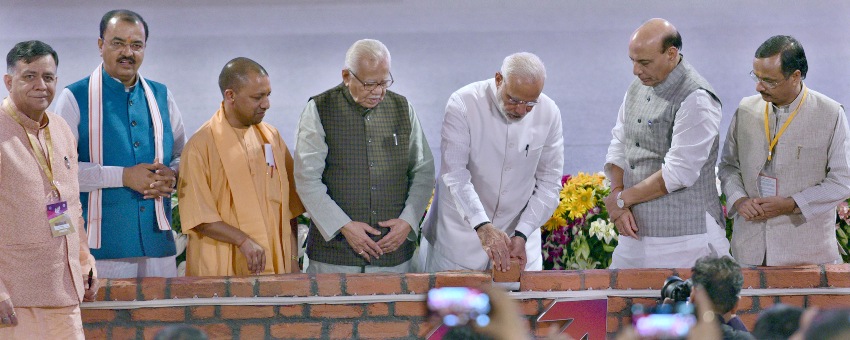 प्रधानमंत्री मोदी एक ईंट पर हस्ताक्षर कर उसे स्थापित करते हुए