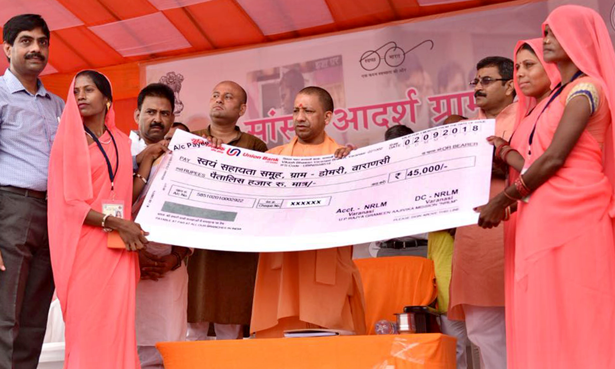 UPCM लाभार्थियों को योजनाओं के स्वीकृति पत्र और चेक प्रदान करते हुए