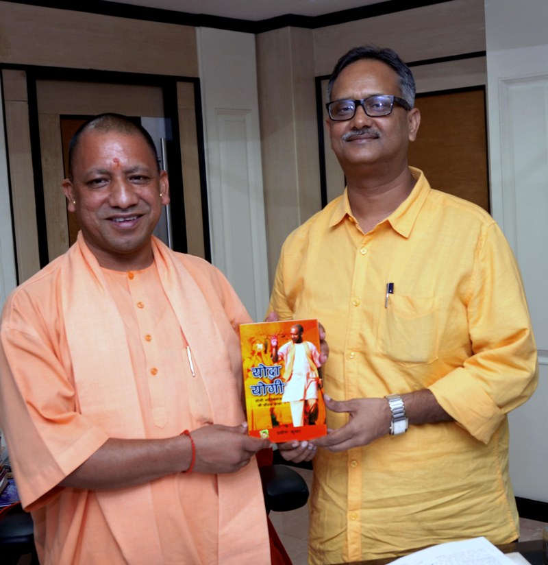 UPCM को प्रवीण कुमार अपनी पुस्तक ‘योद्धा योगी’ की प्रति भेंट करते हुए