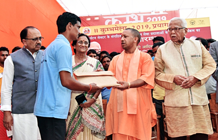 UPCM इलाहाबाद में कुम्भ मेला मार्गदर्शक मण्डल की बैठक के दौरान लाभार्थी को बैग भेंट करते हुए