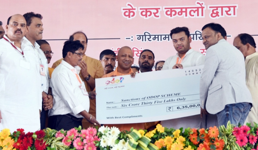UPCM अलीगढ़ में लाभार्थियों को चेक प्रदान करते हुए